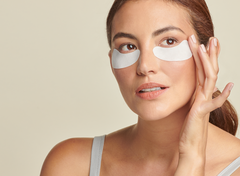 Woman wearing eye patches with a plain background
