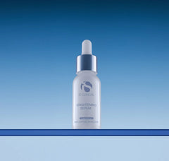 iS Clinical brightening serum bottle on a gradient blue background