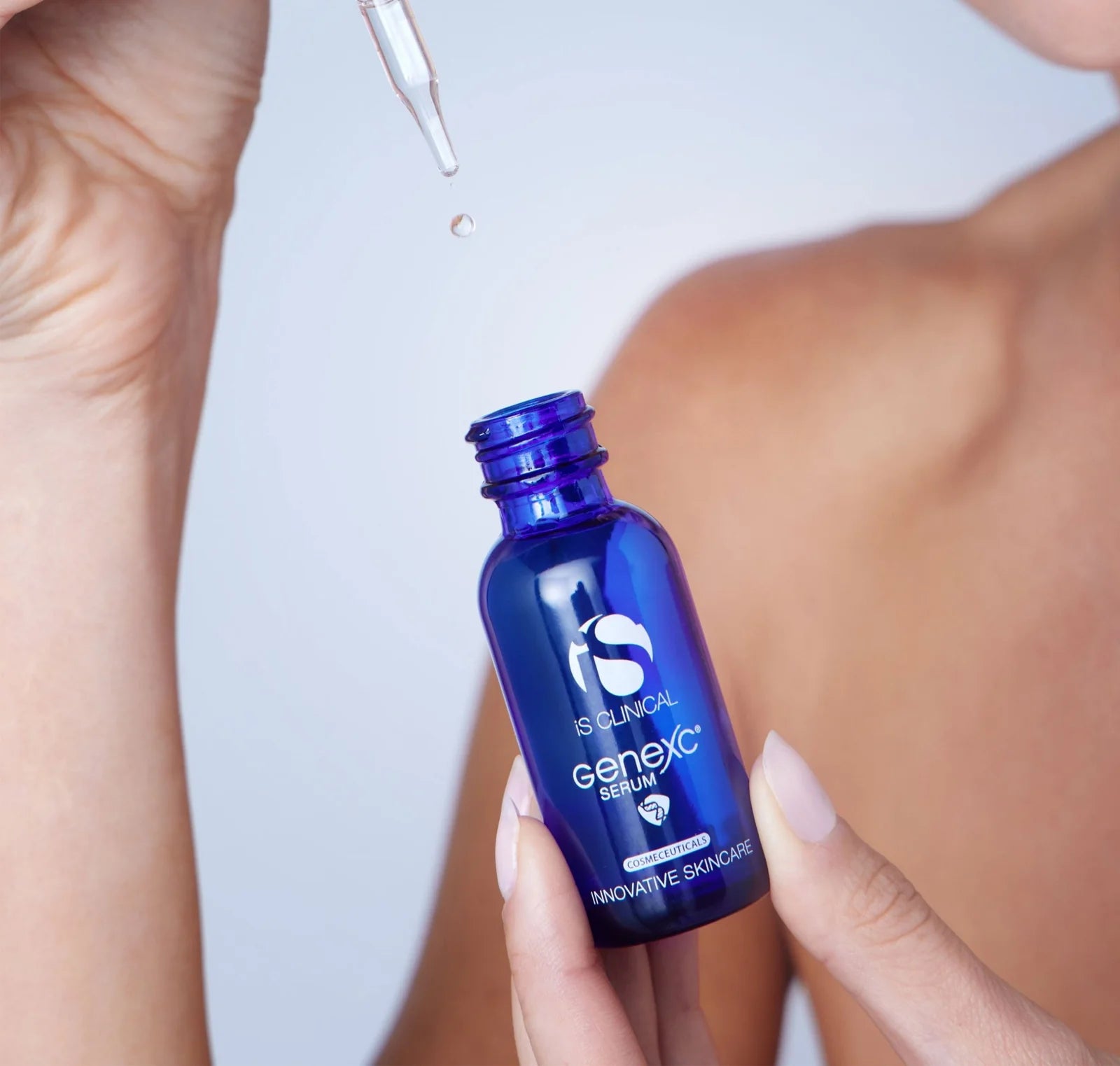 Blue Genexic serum bottle with dropper being used on skin