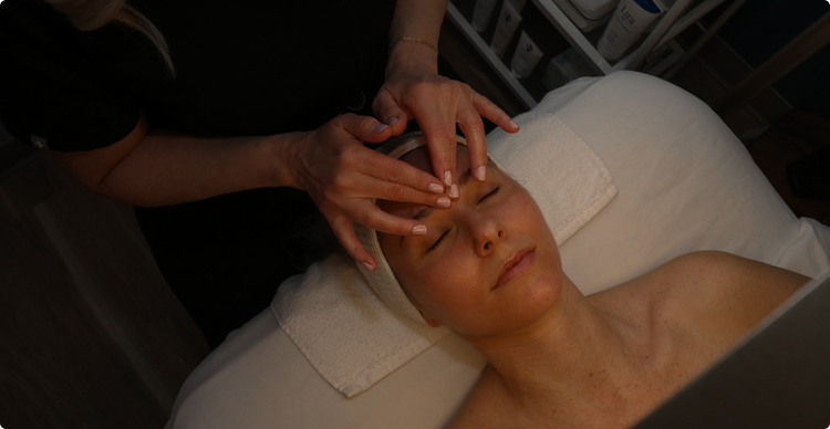 Person receiving a facial treatment with hands applying product to face