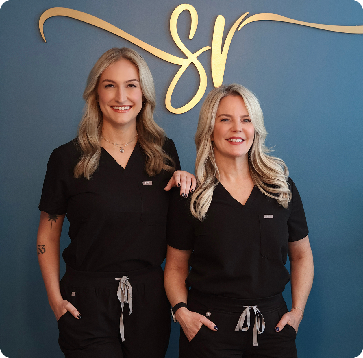Two women in black uniforms standing side by side against a blue background with a decorative 'SR' logo.