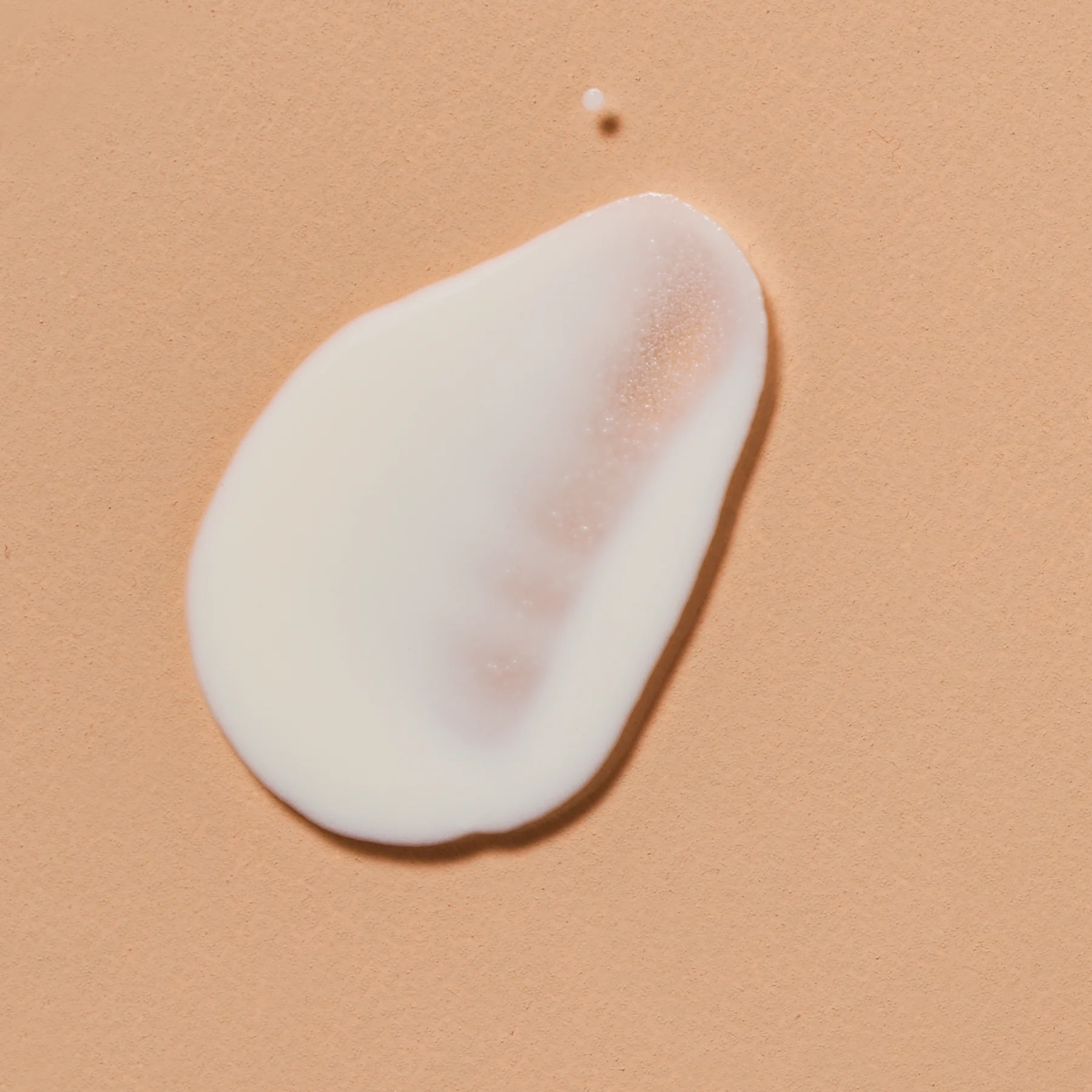 White cream droplet on a beige background