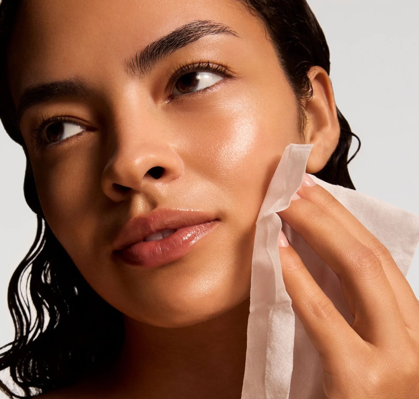 Woman applying a skincare product to her face with a cotton pad.