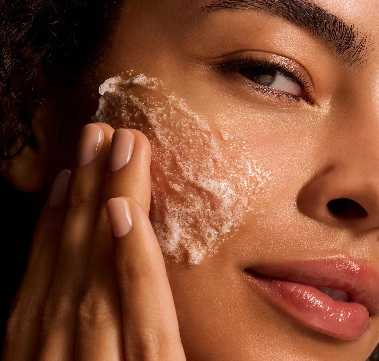 Close-up of a person applying a skincare product to their face.