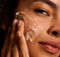 Close-up of a person applying a skincare product to their face.