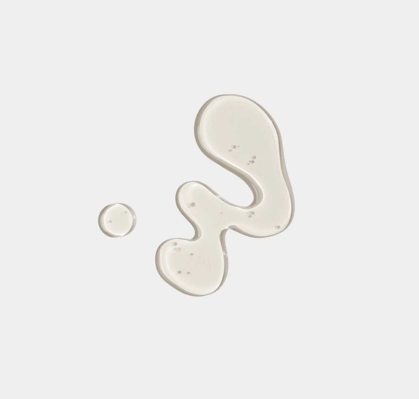 Two droplets of white cream on a light gray background