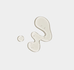 Two droplets of white cream on a light gray background