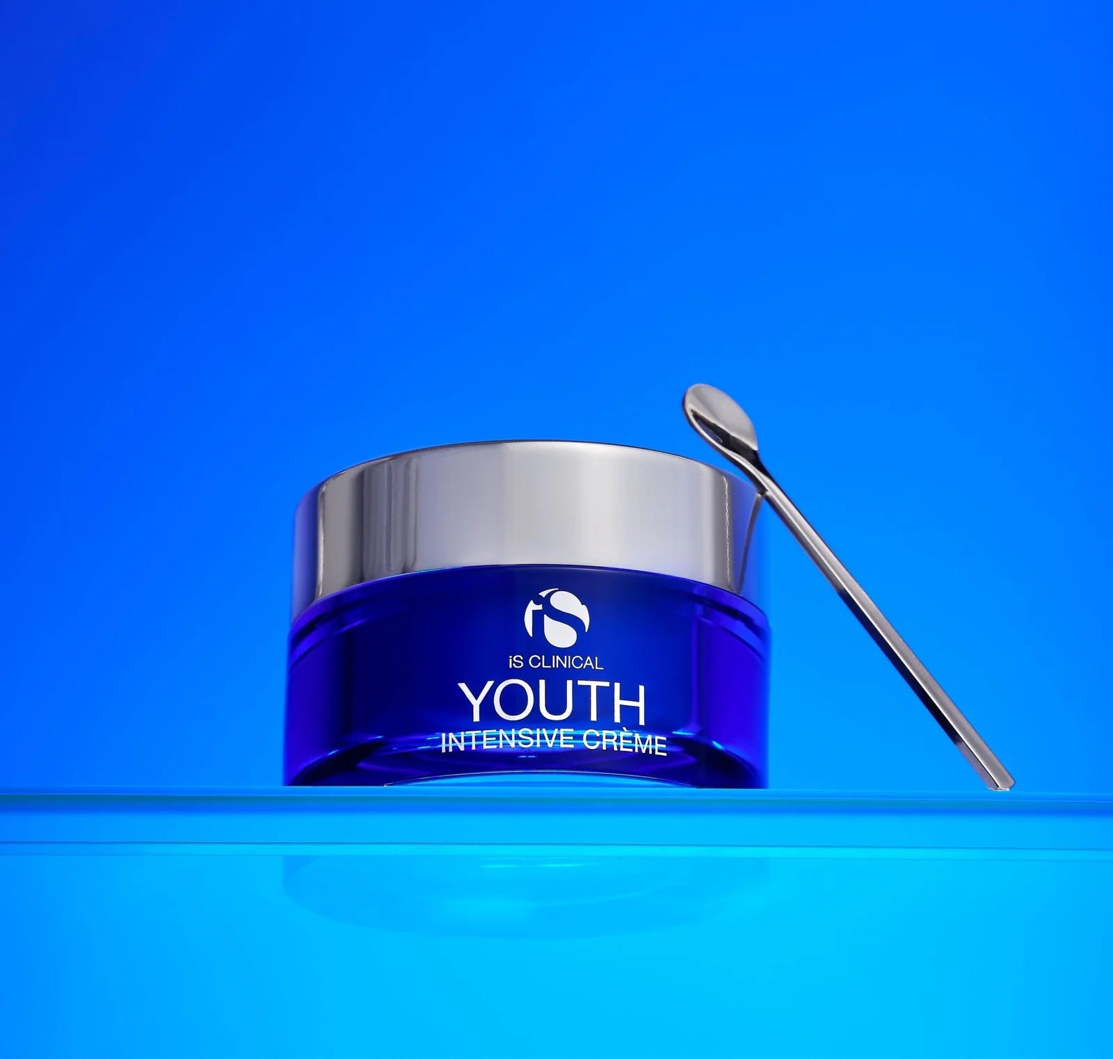 Blue jar of 'Youth Intensive Creme' with a silver applicator on a blue background